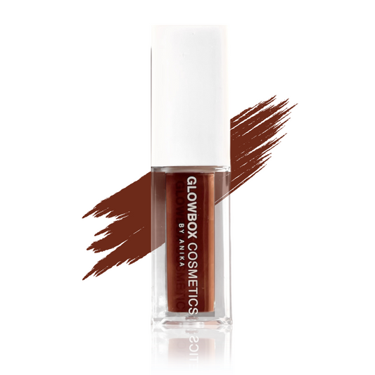 Our Makeda lip gloss in a clear container with a white cap. The gloss is a chocolate brown tint with a thick consistency and is non-sticky. There is a swatch of the brown gloss shade to the back of the gloss tube. The gloss tube reflection is shown to the